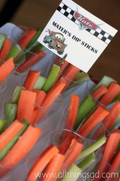 carrots and celery sticks are arranged in plastic cups with signs on them