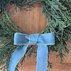 a close up of a wreath on a wooden surface with a blue ribbon tied around it