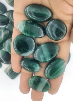 a person's hand holding several green stones