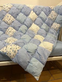 a blue and white quilted blanket sitting on top of a bed