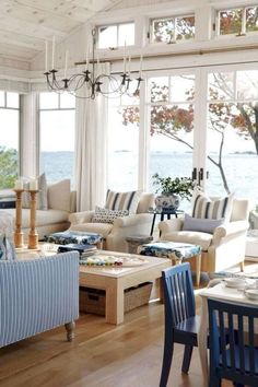 a living room filled with lots of furniture next to a large window covered in windows