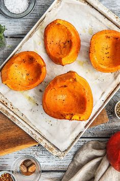 four baked sweet potatoes on a baking sheet with spices and seasonings around the edges