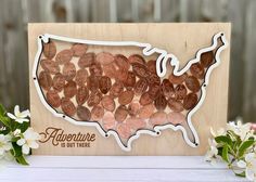 a wooden cutout of the united states made out of penn bills with flowers around it