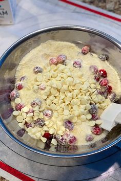 a metal bowl filled with food on top of a counter next to a white and red striped table cloth