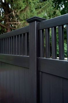 a close up of a black fence with trees in the background