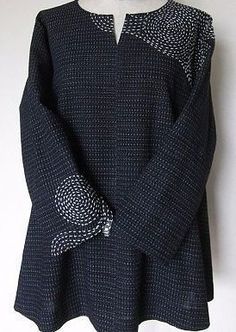 a black sweater with white dots on the shoulders and sleeves, hanging from a mannequin's head