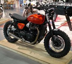 a red motorcycle parked on top of a wooden platform in front of other motorbikes