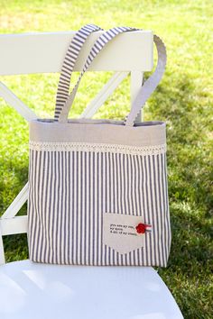 a striped tote bag sitting on top of a white chair in front of grass