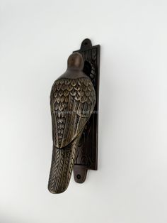 a bird shaped wall mounted on the side of a white wall with a black metal hook