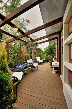 an outdoor covered patio with lounge chairs and potted plants on the side walk way