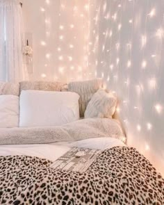 a leopard print comforter on a bed with white sheets and lights in the background