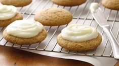 some cookies are cooling on a rack with icing and a spoon next to them