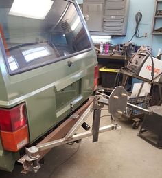 the back end of a green van in a garage with tools and equipment on it