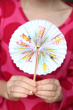 a person holding a paper fan in their hands