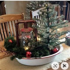 a christmas tree in a bowl with lights and ornaments on the table next to it