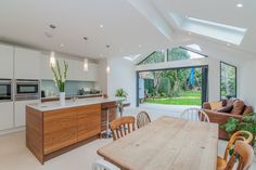 an open kitchen and dining room area with skylights on the ceiling, windows to outside