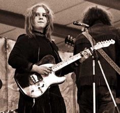 a woman standing next to a man holding a guitar