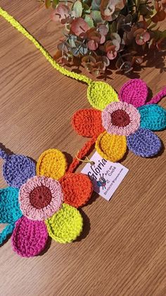 a crocheted necklace with flowers is sitting on a table