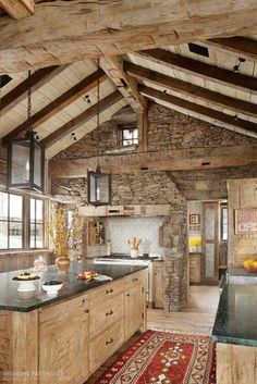 a rustic kitchen with stone walls and wooden beams, black counter tops and an island in the middle