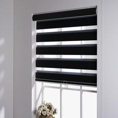 a window with black blinds and flowers on the windowsill