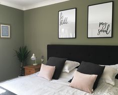 a bed with two pictures on the wall above it and some pillows in front of it