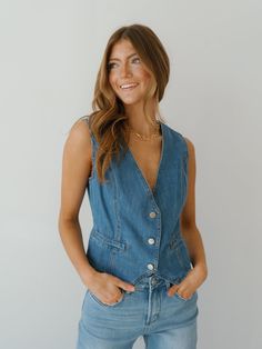 Embrace western flair in the "Nicolette Denim Vest!" A versatile option for wearing with any jeans or skirts, this vest is both versatile and elevated! It features a medium wash color, v-neckline, sleeveless sides, and button front. This vest is a piece that you will turn to again and again this fall! Detailed Fit: V-neck denim vest 3 button up closure Overall Fit: Fitted with no stretch Sizing: True to size Fabric: 85% cotton, 15% polyester Care: Hand wash cold, do not bleach, line dry, low iro Summer V-neck Denim Blue Denim Vest, Fitted Medium Wash Denim Button-up Vest, Fitted Denim Vest With V-neck, Button-up Cotton Denim Vest With Pockets, Medium Wash Button-up Denim Vest With Pockets, Denim Vest, Button Up, Overalls, Turn Ons