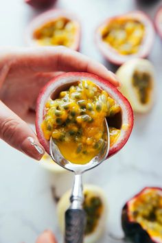 a person holding a spoon with some food inside of it on top of a table