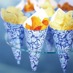 four cups filled with chips on top of a glass table covered in blue and white designs