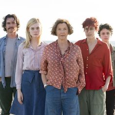 four people standing next to each other on the beach