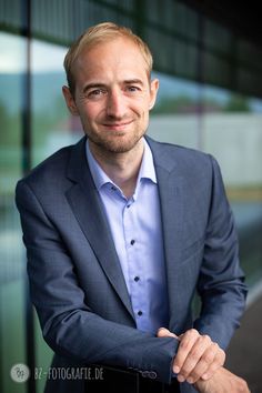 a man in a suit and tie posing for the camera with his arms folded out