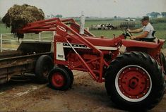 a man driving a red tractor down a dirt road