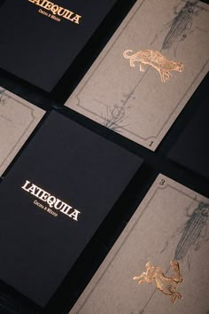 four business cards with gold foil on black paper and the words atescua written in gold