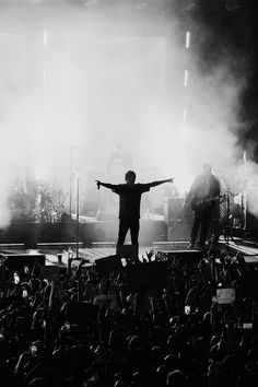 a man standing on top of a stage with his arms outstretched in front of him