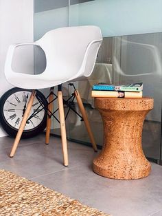 a white chair sitting next to a small table with books on it and a clock in the background