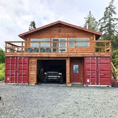 a truck is parked in front of a wooden building with red shipping containers around it