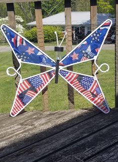 a stained glass butterfly with american flags on it's wings sitting on a wooden deck