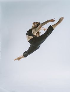 a woman is jumping in the air with her arms outstretched and legs spread out,