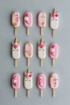 unicorn lollipops with pink and white frosting on them are arranged in a row