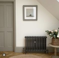 a room with a radiator, table and flowers on the floor next to it