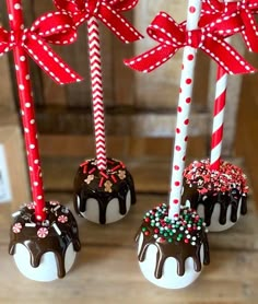 three chocolate covered candy lollipops with bows on them