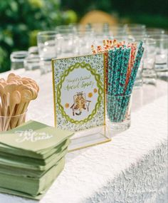 a table topped with lots of glasses filled with different colored straws and paper napkins