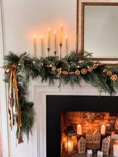 a fireplace decorated for christmas with candles and garland