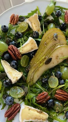 a white plate topped with green salad and blueberries