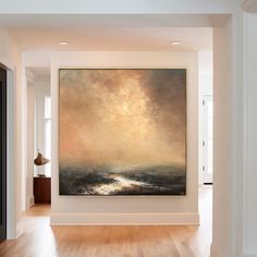 a large painting hanging on the side of a wall in an empty room with hard wood flooring