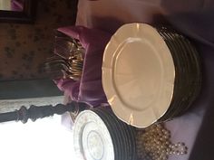 a table topped with plates and silverware next to a purple cloth covered tablecloth