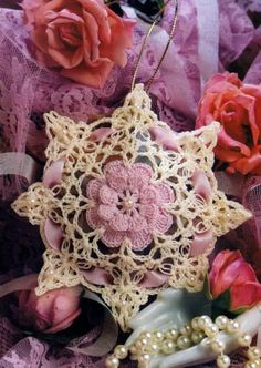 an ornament made out of crochet and beads on lace with flowers