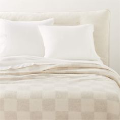 a bed with white sheets and pillows on top of it