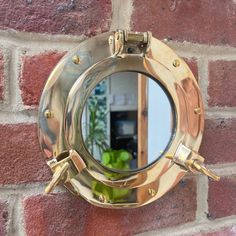 a mirror mounted to the side of a brick wall next to a potted plant