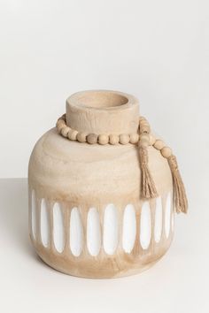 a white vase with beads and tassels on it