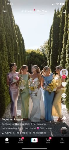 a group of women standing next to each other in front of some trees and bushes